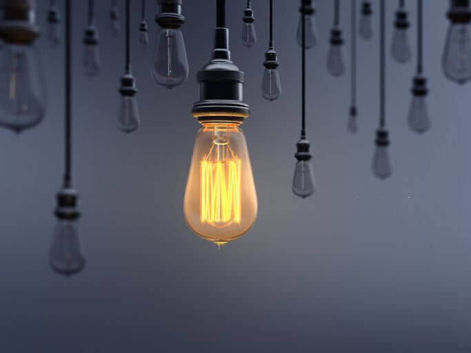 Glowing Light Bulb between the others on dark background. Can be used leadership, innovation and individuality concepts.  (3d render)